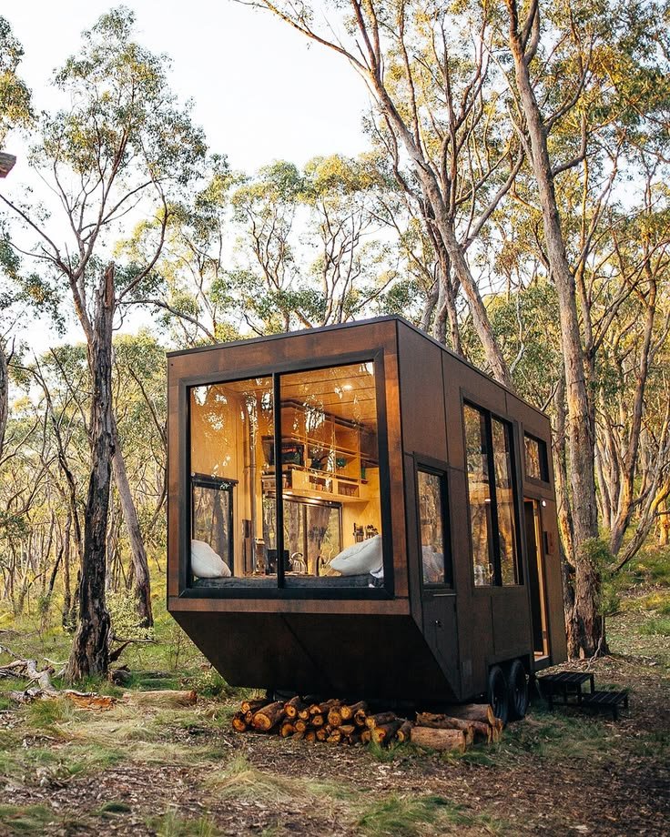 This may contain: a small cabin in the middle of some trees with windows on it's sides
