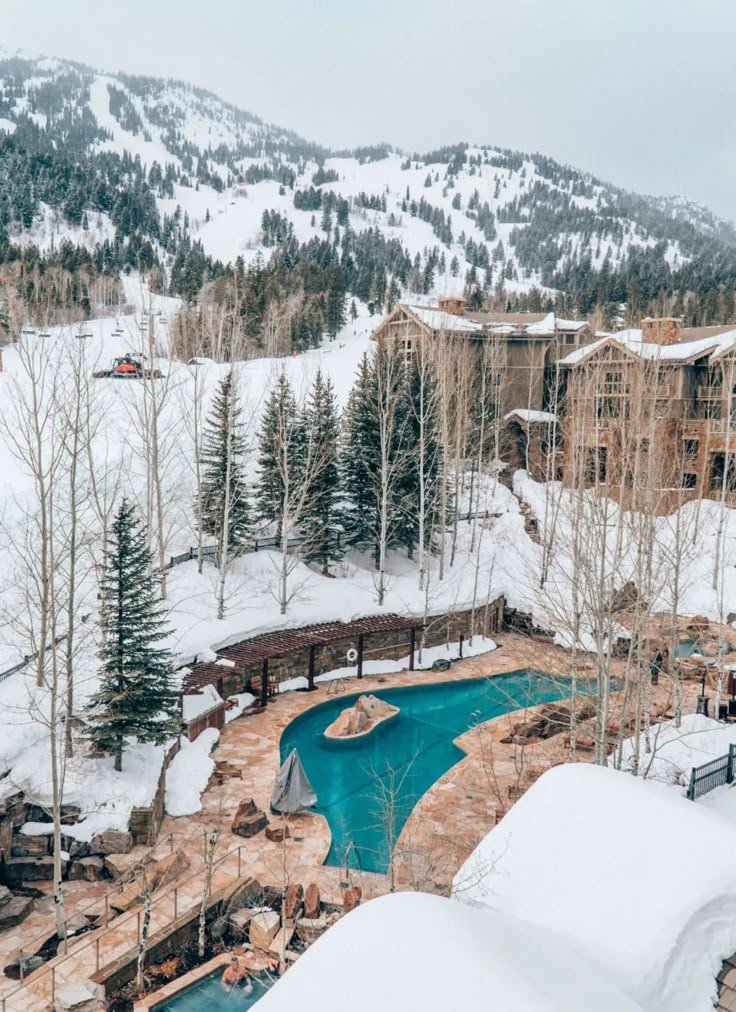 This may contain: an aerial view of a resort in the mountains with snow on the ground and trees