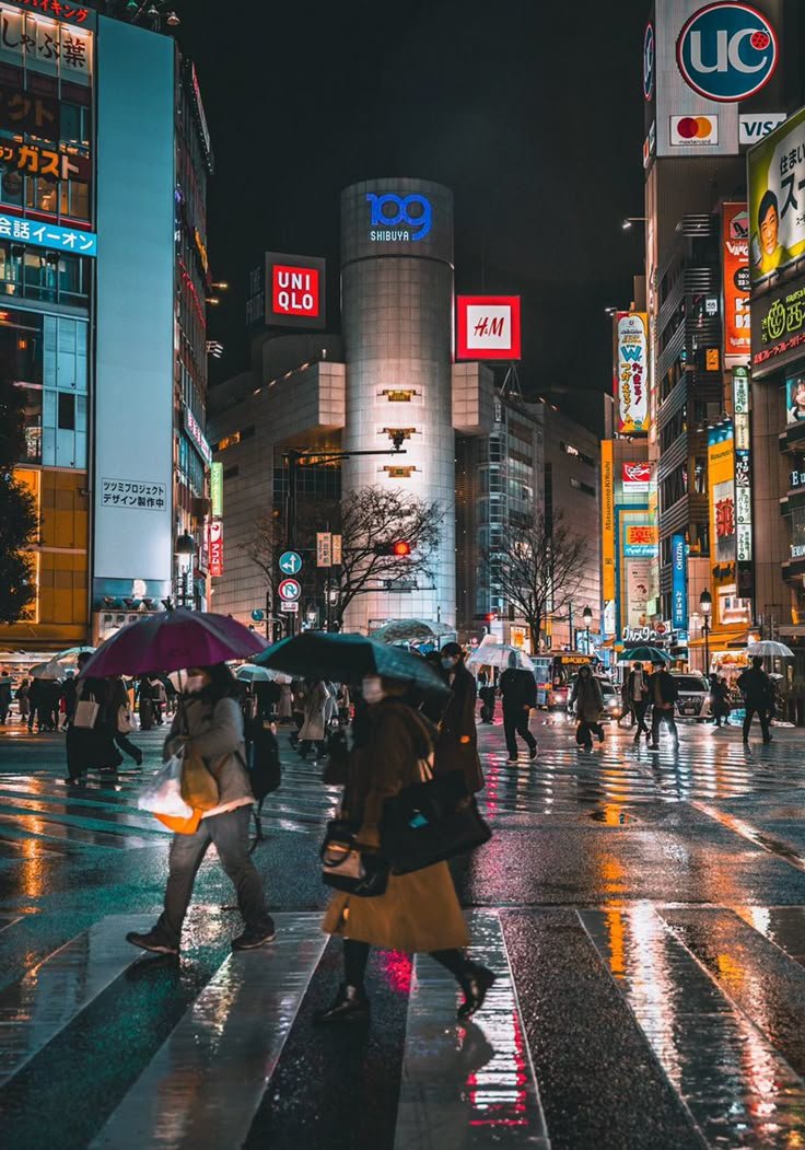 This may contain: people crossing the street at night with umbrellas