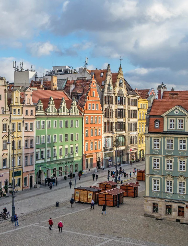 This may contain: people are walking around in an old european city with colorful buildings and cobblestone streets