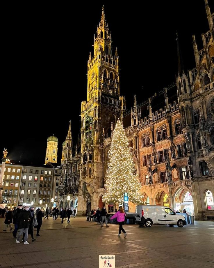 This may contain: people walking around in front of a large building with a lit christmas tree on it