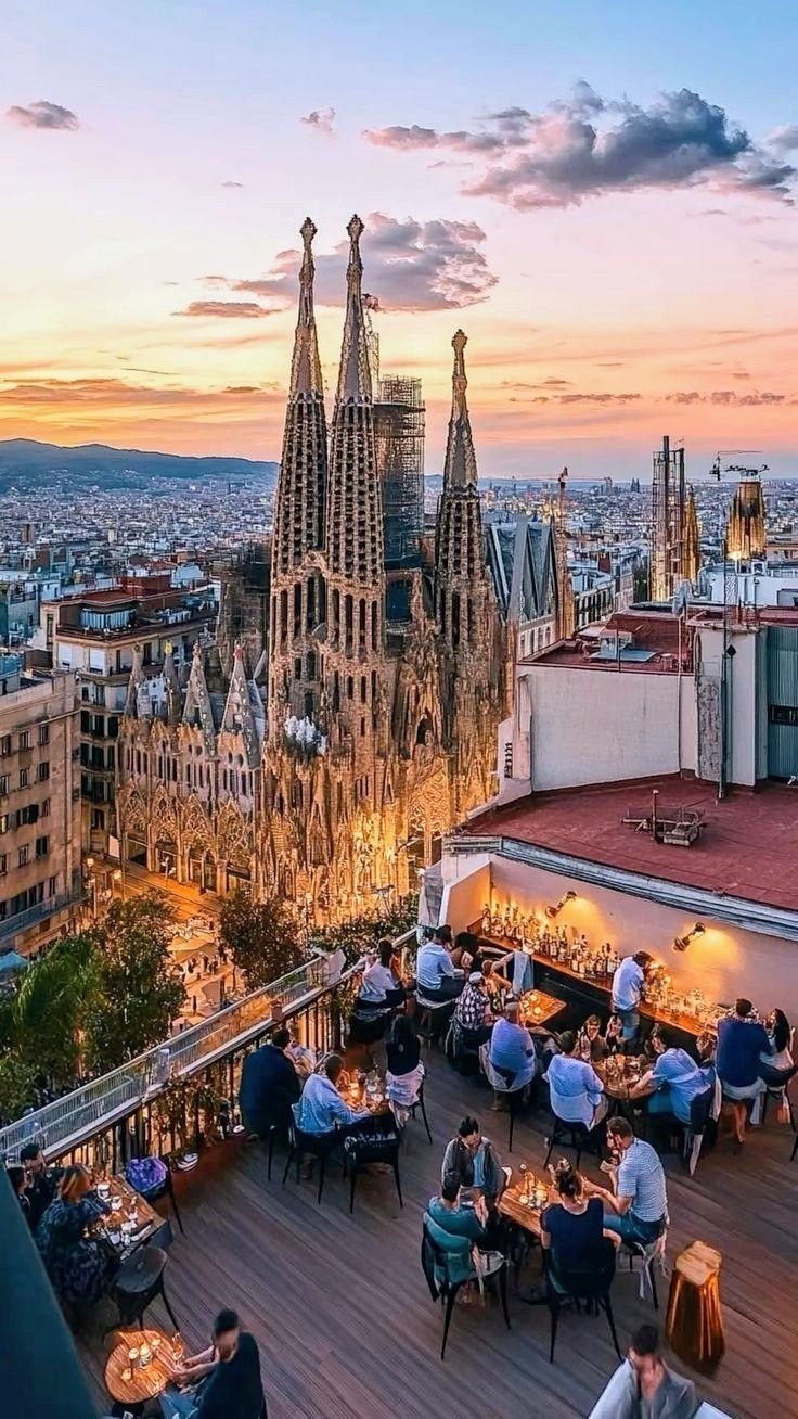 This may contain: people sitting at tables on top of a roof in front of the cityscape