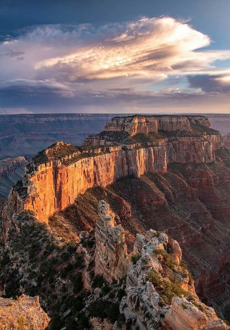 This may contain: the grand canyon at sunset with clouds in the sky and sun shining down on it