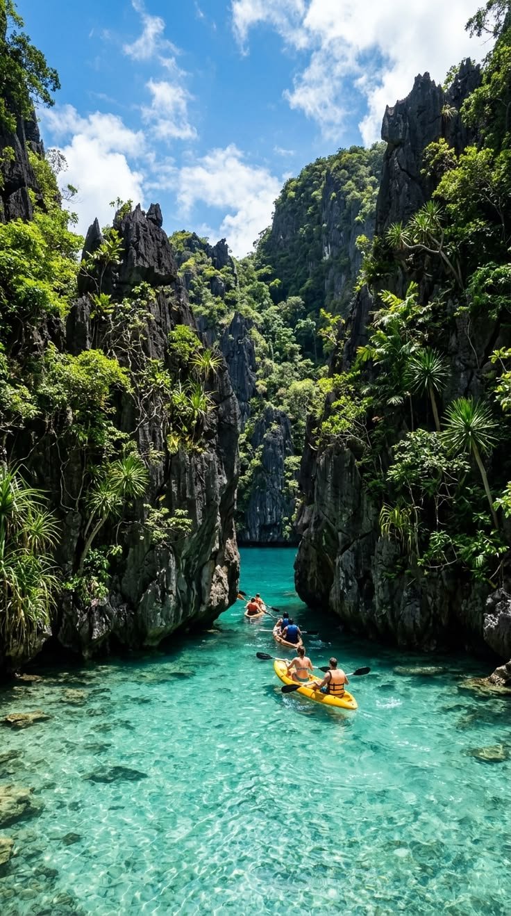 This may contain: three people are kayaking in the clear blue water near some cliffs and trees on either side