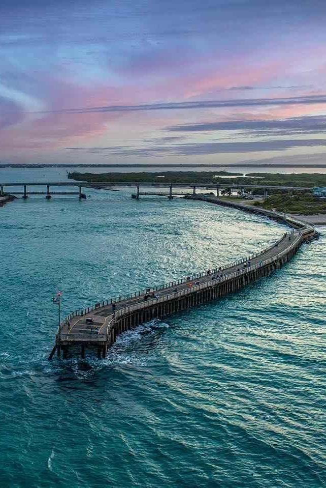 This may contain: an aerial view of a pier in the middle of the ocean at sunset or sunrise