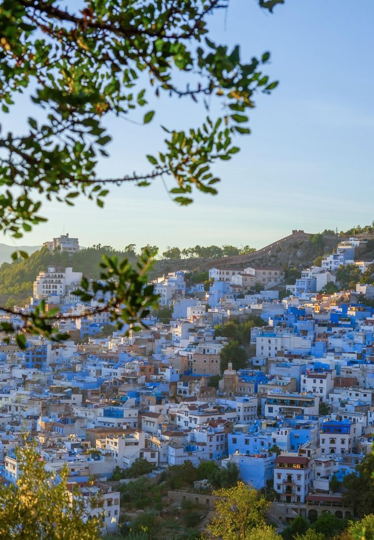 This may contain: the blue city is surrounded by hills and trees