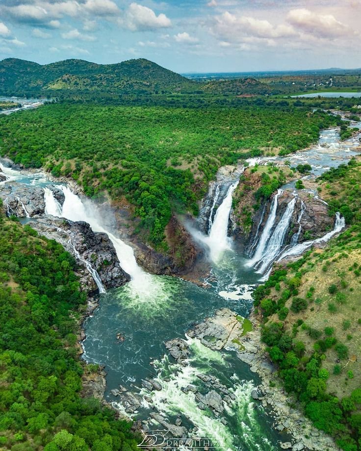 This may contain: an aerial view of a waterfall in the middle of trees and water with mountains in the background