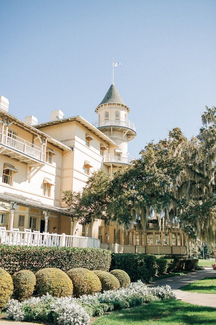 This may contain: a large building with a clock tower next to some bushes and trees in front of it