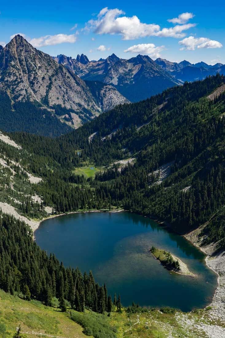 This may contain: a lake surrounded by mountains and trees in the middle of a valley with lots of water
