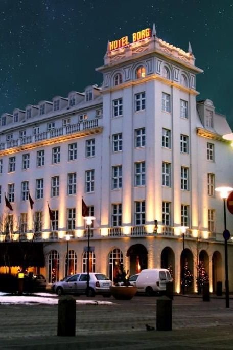 This may contain: the hotel is lit up at night with stars in the sky above it and cars parked outside