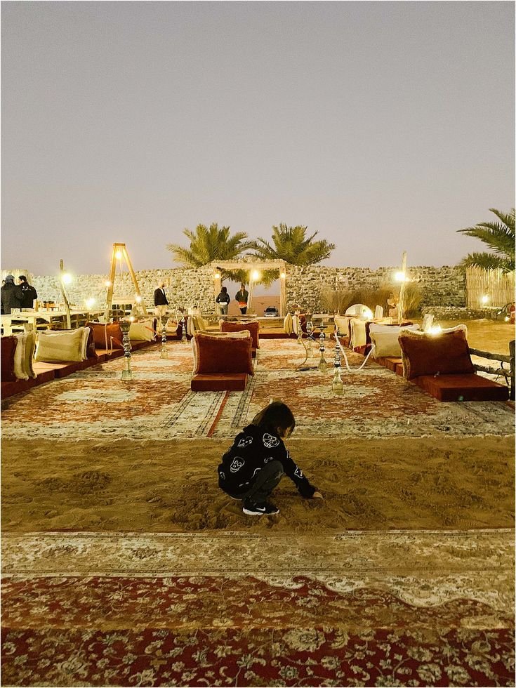 This may contain: a person kneeling on the ground in front of some couches and tables at night