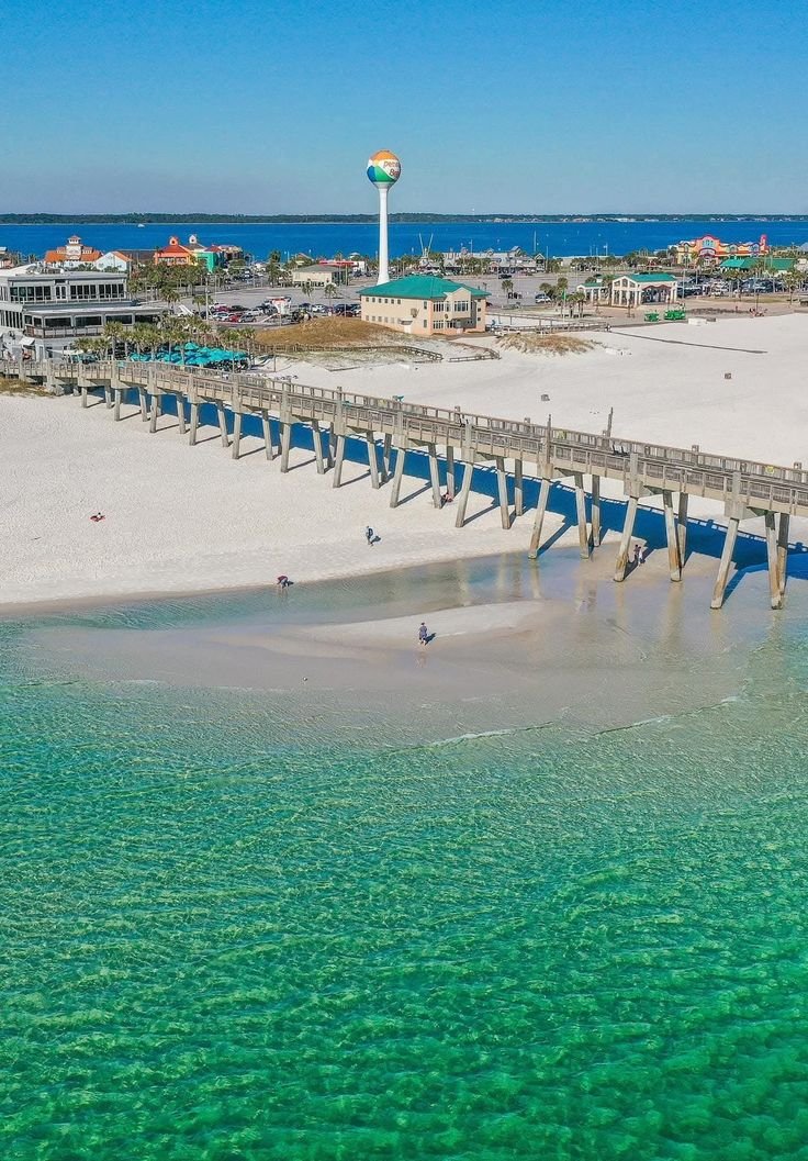 This may contain: an aerial view of the beach and pier in destinia, florida with clear blue water