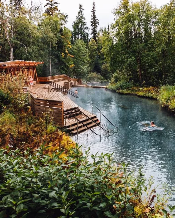 This may contain: a man swimming in a river next to a wooden dock