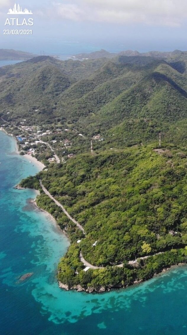 This may contain: an aerial view of the ocean and land in front of some hills with trees on them