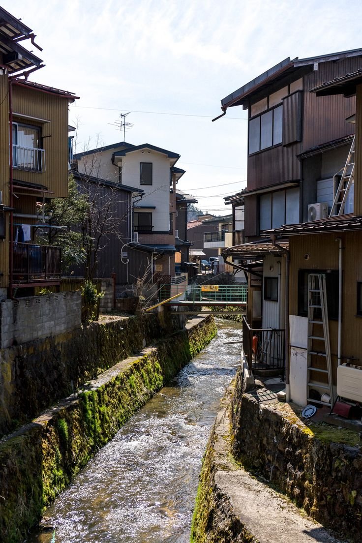 This may contain: a river running through a small town next to tall buildings