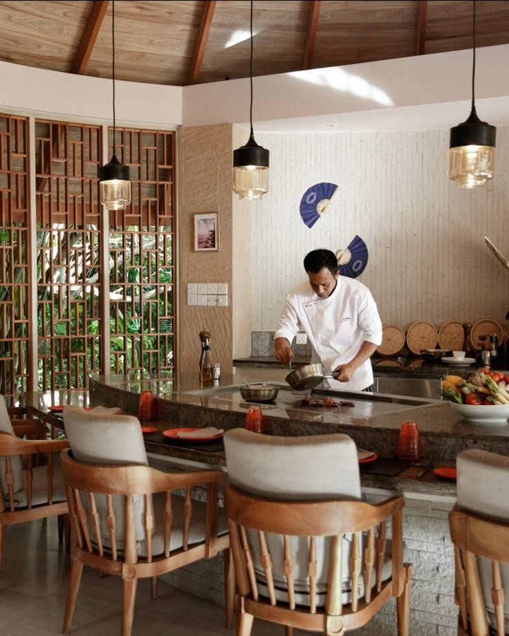 This may contain: a man preparing food in a kitchen with lots of counter space and chairs around it