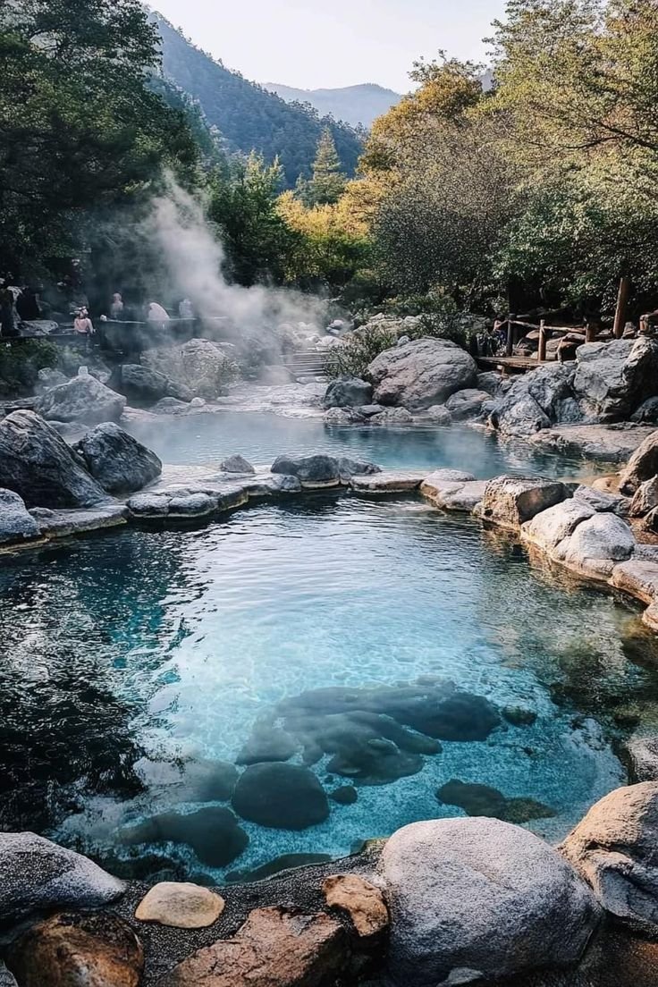 This may contain: a hot spring surrounded by rocks and water