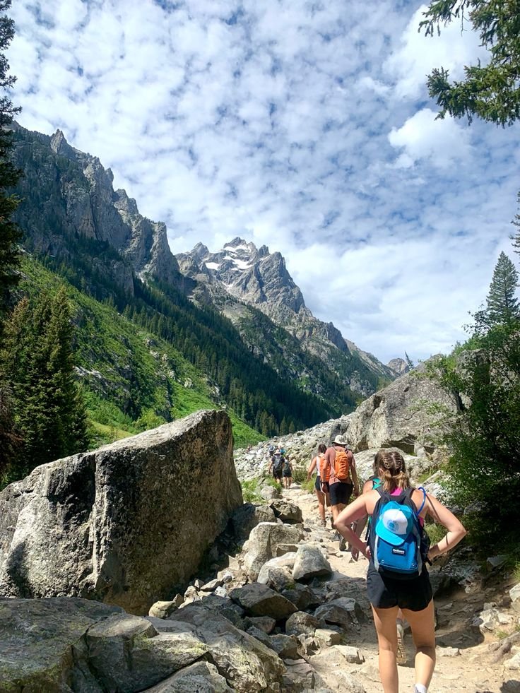 This may contain: several people hiking up a rocky trail in the mountains