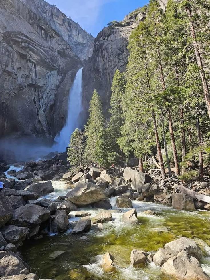This may contain: there is a waterfall in the middle of some rocks and trees on the other side