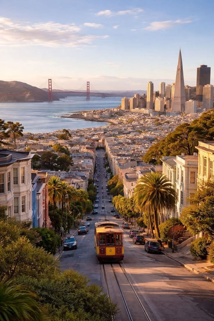 This may contain: an aerial view of san francisco with the golden gate bridge in the distance and trolley cars on the road