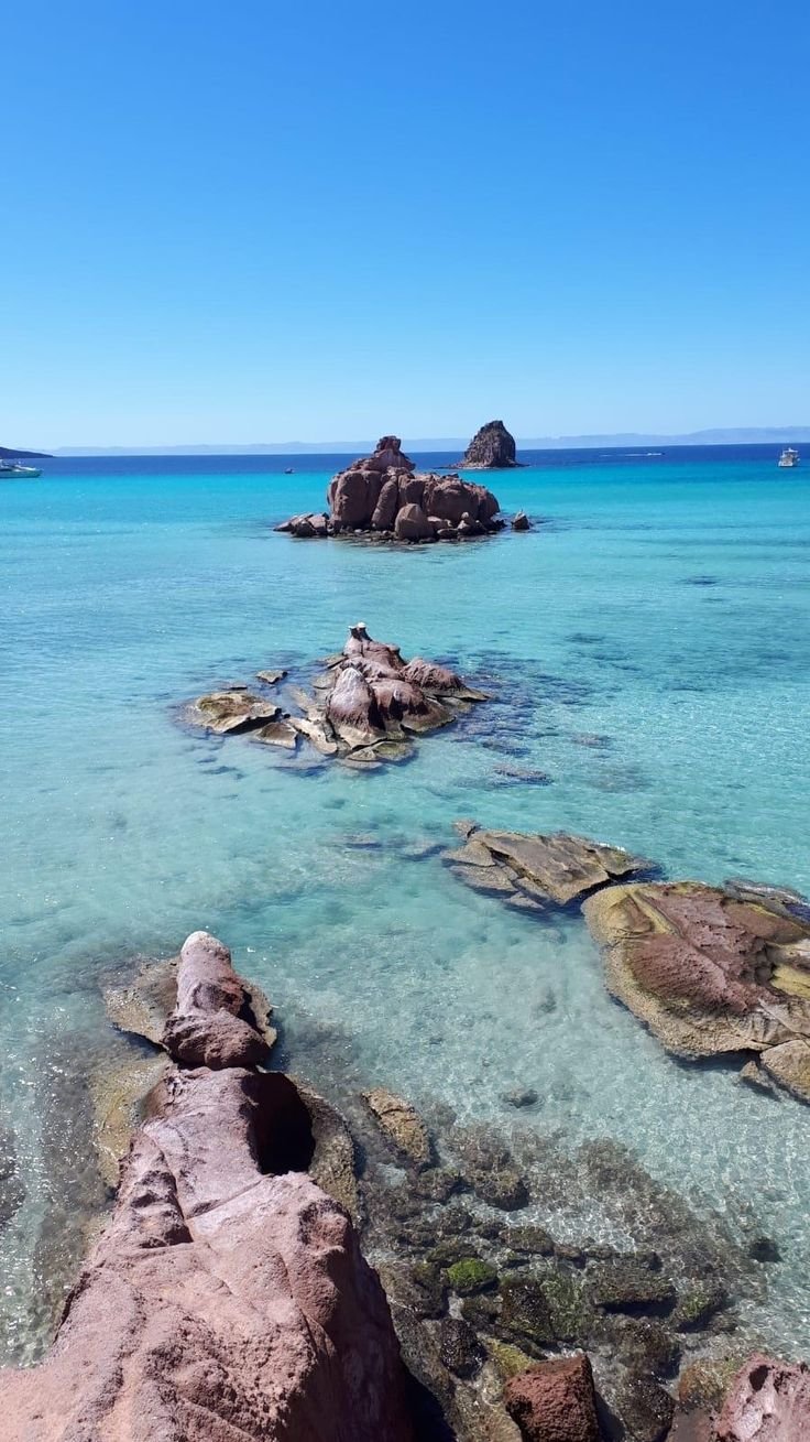 This may contain: the water is crystal blue and clear with rocks