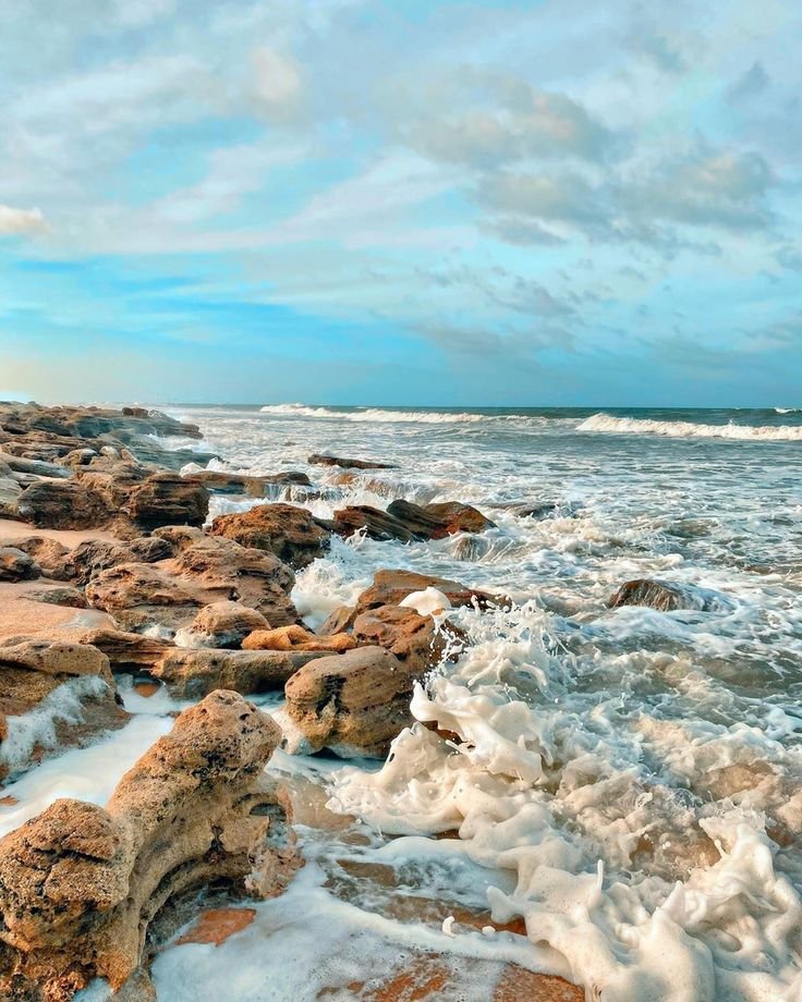 This may contain: the ocean is covered in ice and rocks as it sits on the beach near the shore