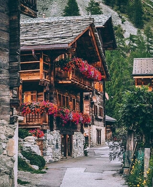 This may contain: an old wooden house with flowers on the balconies