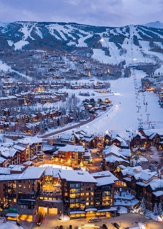 This may contain: an aerial view of a ski resort and surrounding buildings at night time with snow on the ground