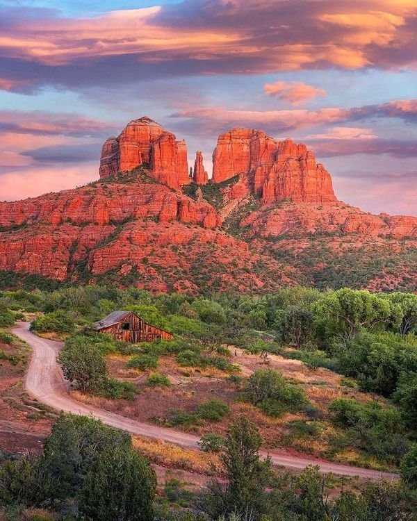This may contain: the red rocks are in the distance and there is a dirt road going through them