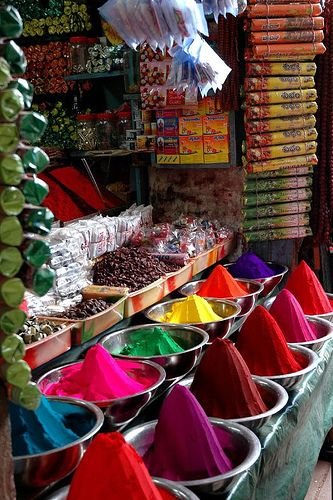 This may contain: there are many different colored powders on display in this market stall, including red, yellow, green and blue