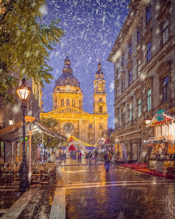 This may contain: an image of a city street at night with rain falling on the ground and people walking around