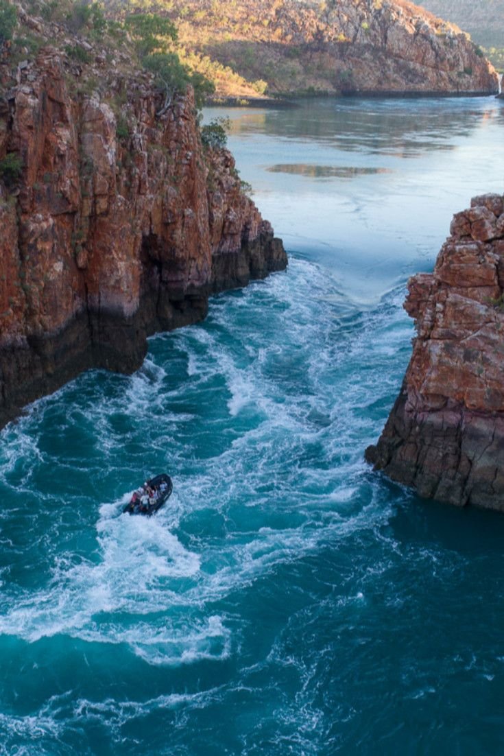 This may contain: a boat is in the water near some rocky coastlines and cliffs that look like they have been carved out of rocks