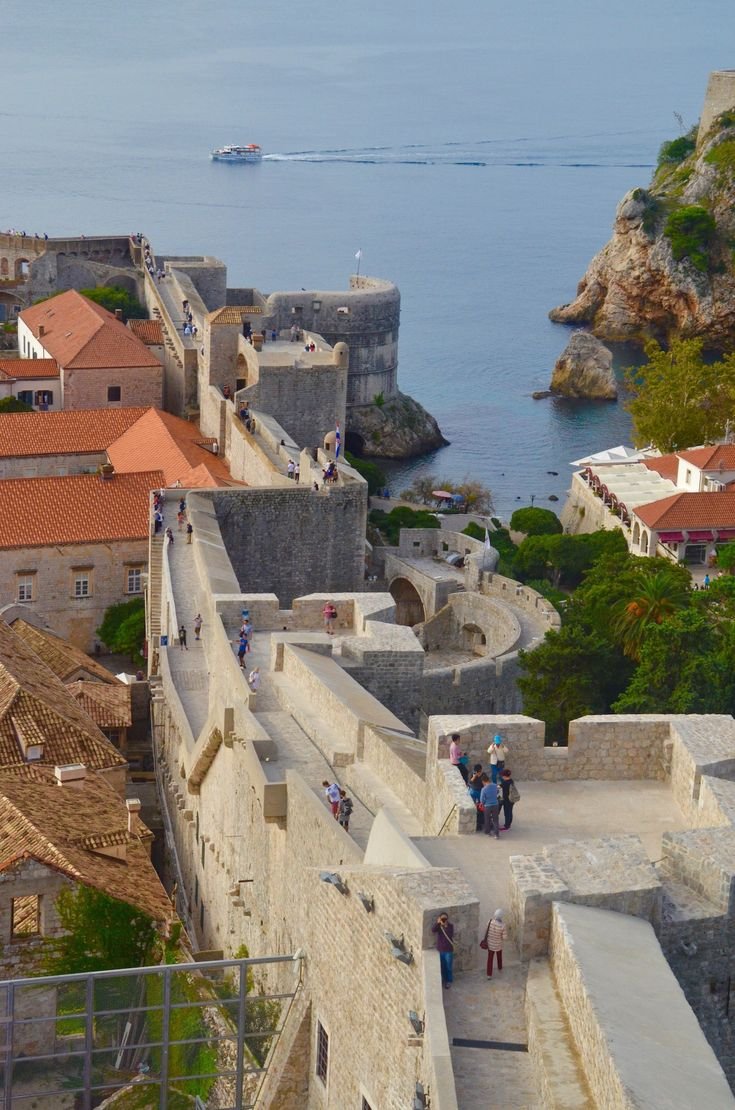 This may contain: people are walking up and down the stairs in an old city by the sea with boats
