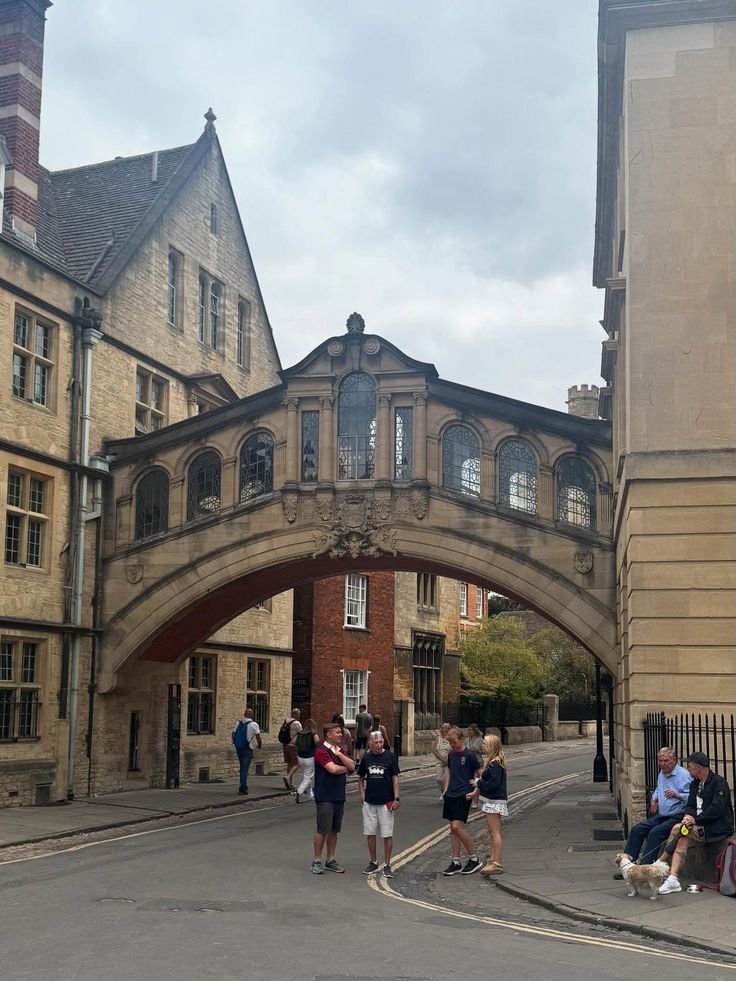 This may contain: some people are standing in front of an old building with a stone arch over it