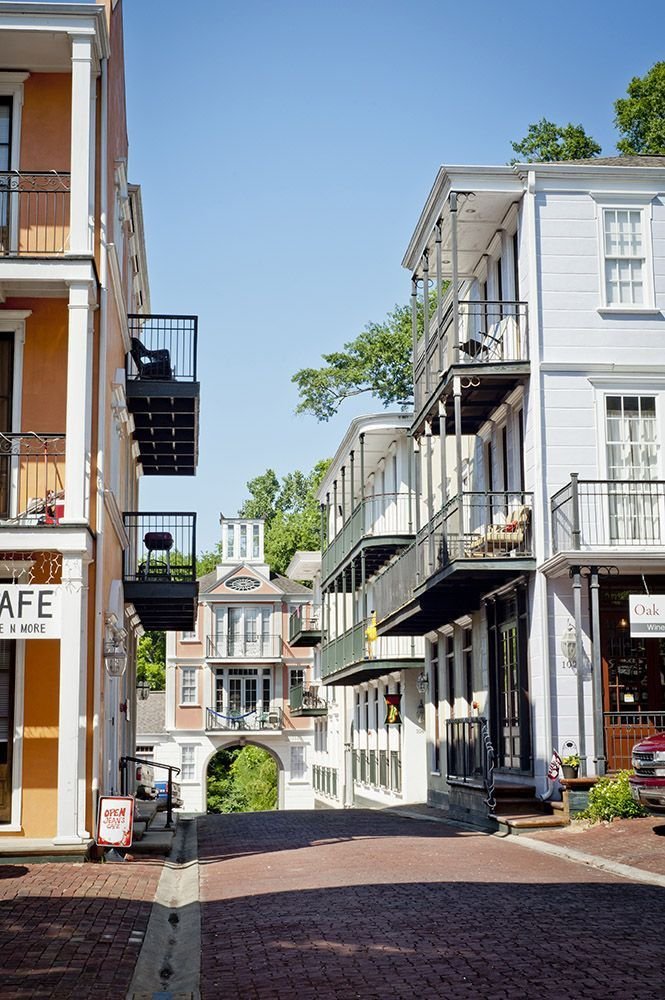 This may contain: an empty street with several buildings on each side and balconies in the middle