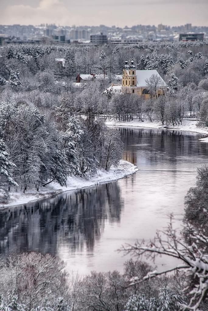 This may contain: a river running through a forest covered in snow