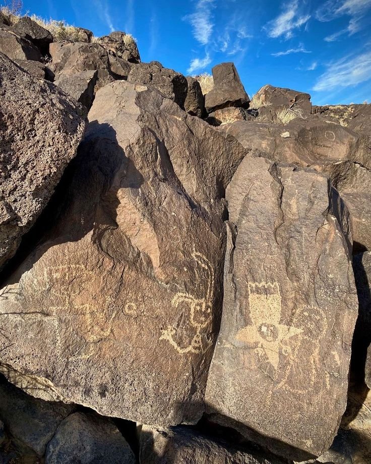 This may contain: some rocks with drawings on them under a blue sky