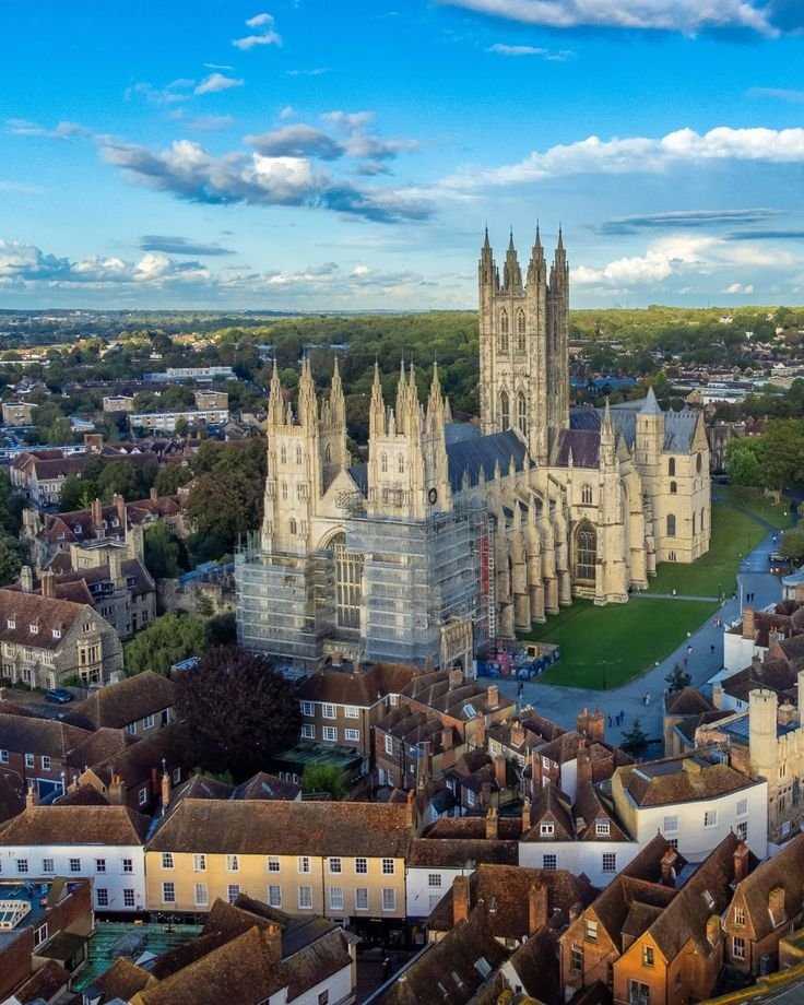 This may contain: an aerial view of the cathedral and surrounding buildings in england, with blue skies above