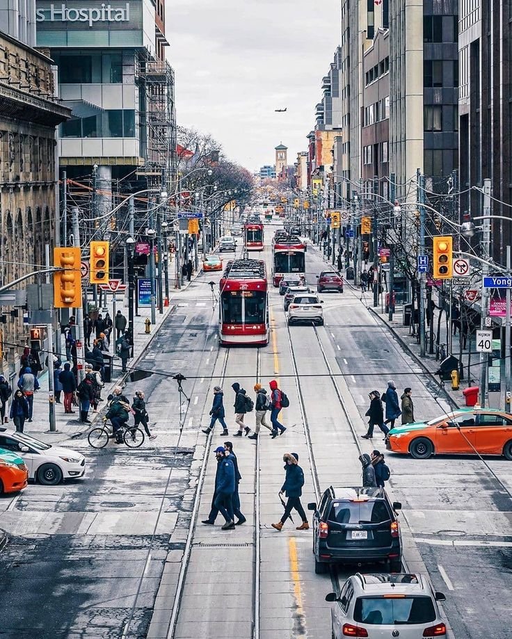 This may contain: people crossing the street at an intersection on a cloudy day