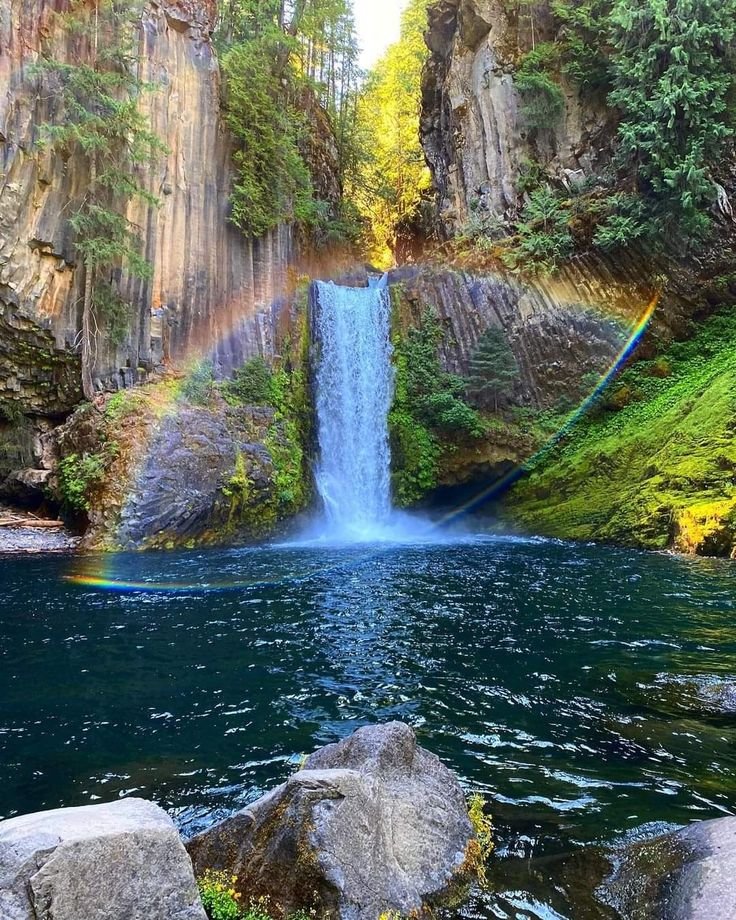 This may contain: a waterfall with a rainbow in the background