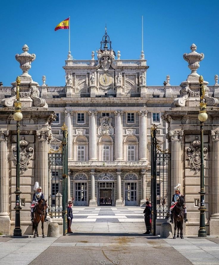 This may contain: two men on horses standing in front of a large building with columns and flags flying