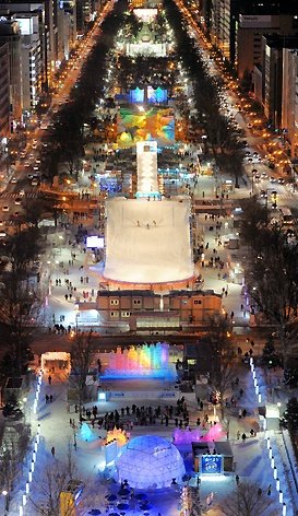 This may contain: an aerial view of a city at night with many lights on the buildings and people walking around