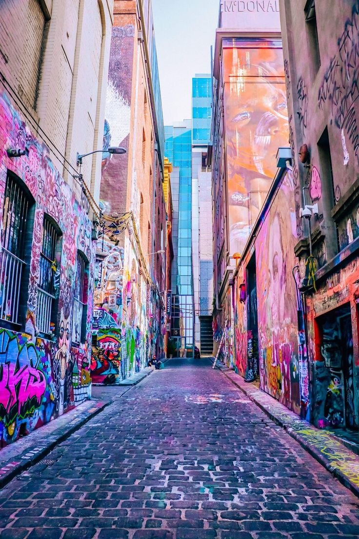 This may contain: an alleyway with graffiti all over the walls and buildings on both sides, in between two streets