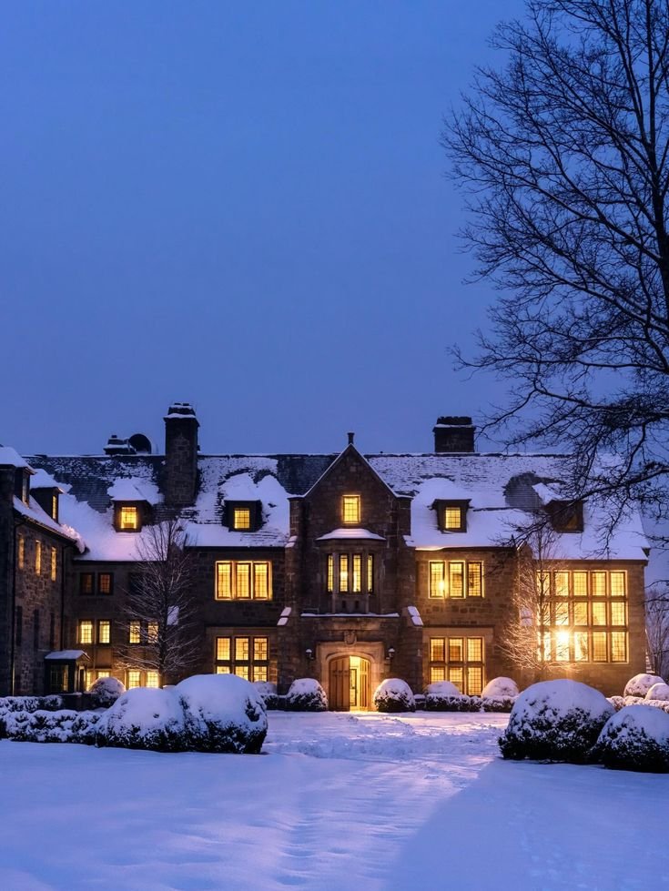This may contain: a large house is lit up at night in the snow with lights shining on it's windows