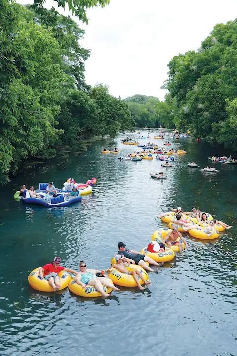 This may contain: many people are floating down the river on rafts and inflatables,