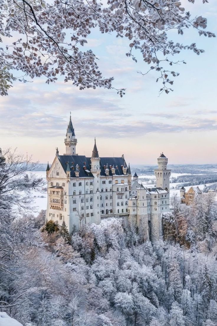 This may contain: an old castle is surrounded by snow covered trees