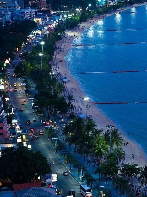 This may contain: an aerial view of the beach and ocean at night, with traffic on the road