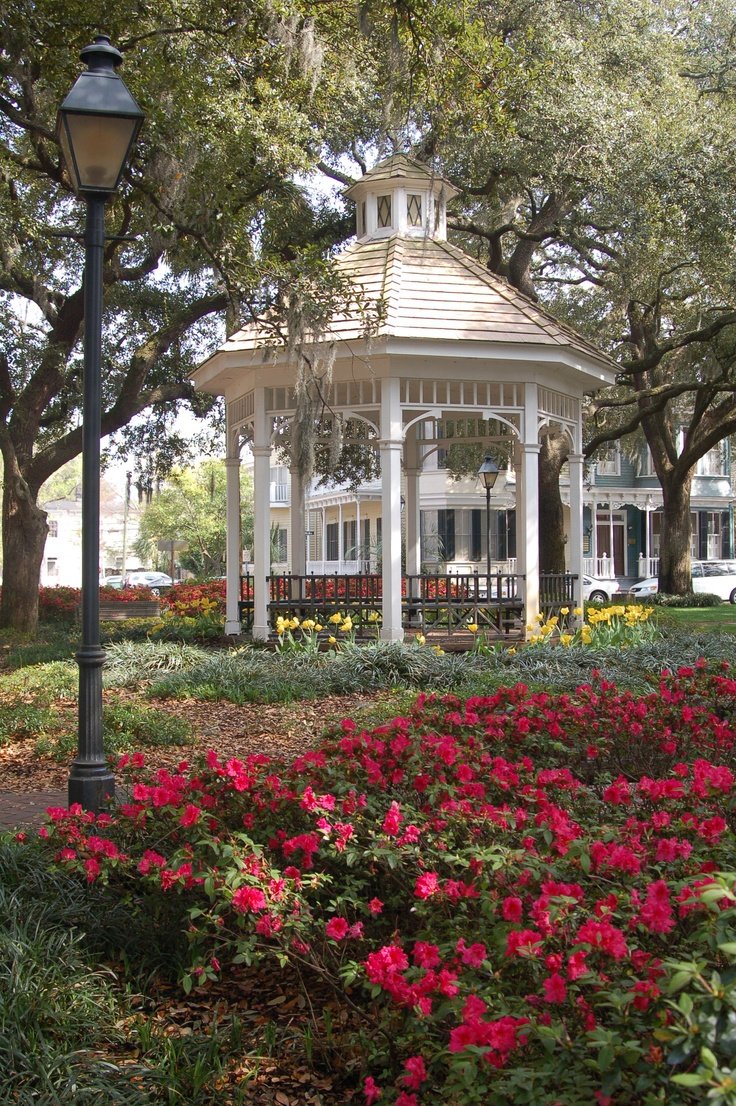 This may contain: a white gazebo surrounded by flowers and trees