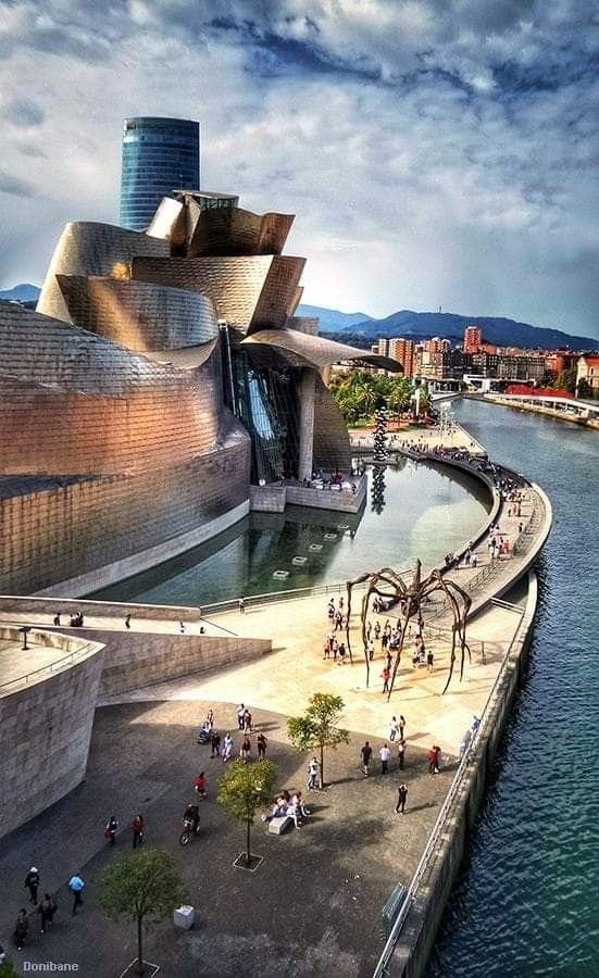 This may contain: an artist's rendering of a building next to the water with people walking around it