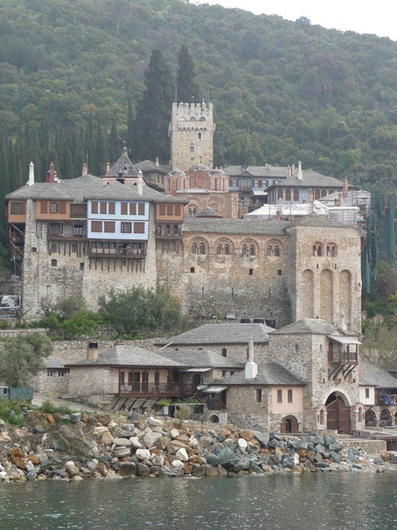 This may contain: an old building sitting on top of a hill next to a body of water